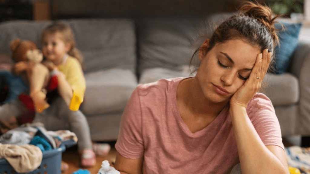 Mãe cansada com crianças ao fundo.